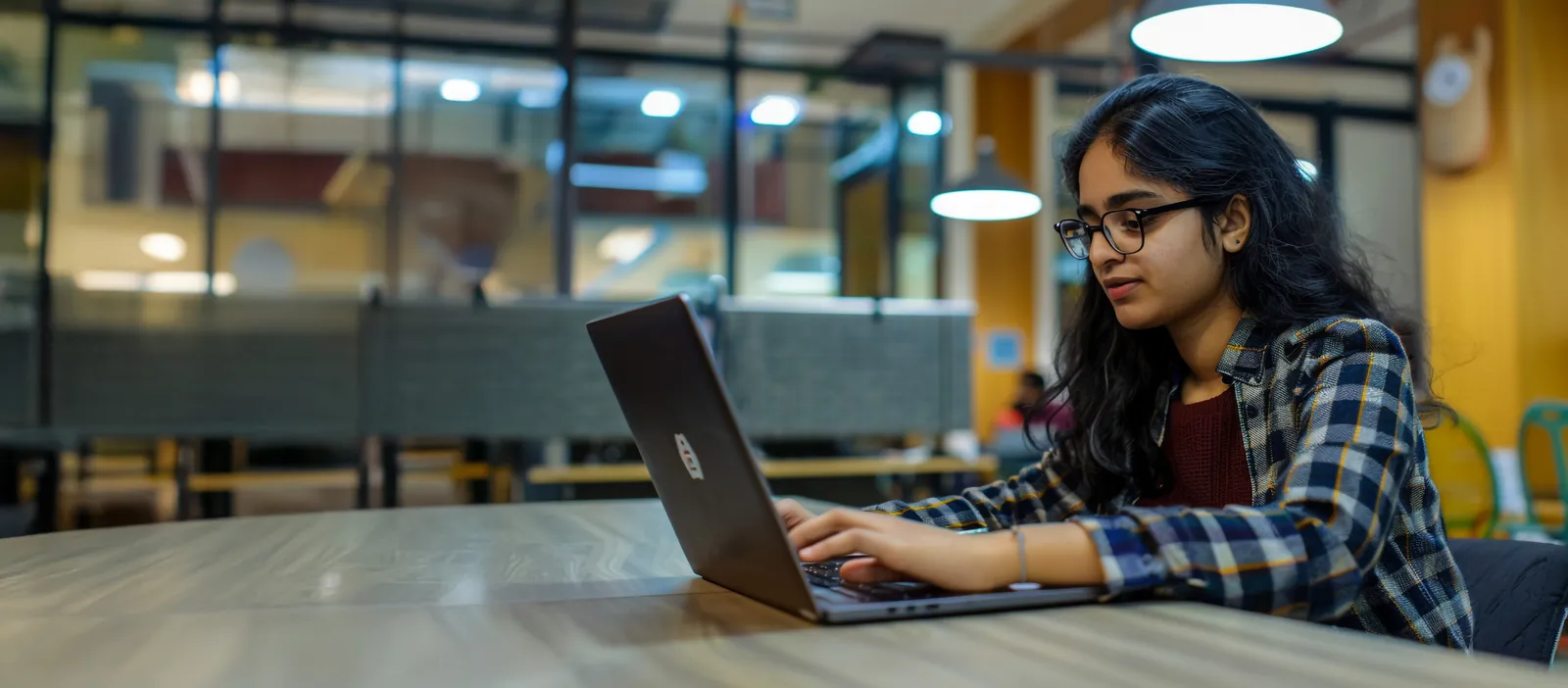 A Mahalakshmi College for Girls student studying on a laptop in a campus study lounge